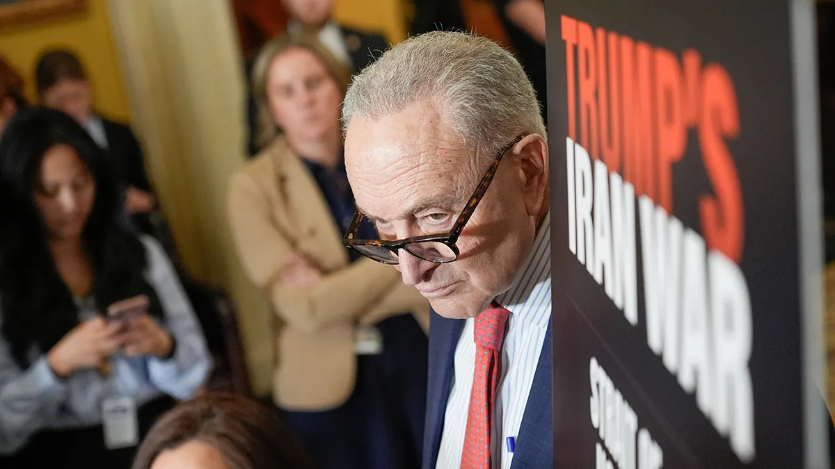 Chuck Schumer sluša dok stoji za govornicom tijekom konferencije za novinare.