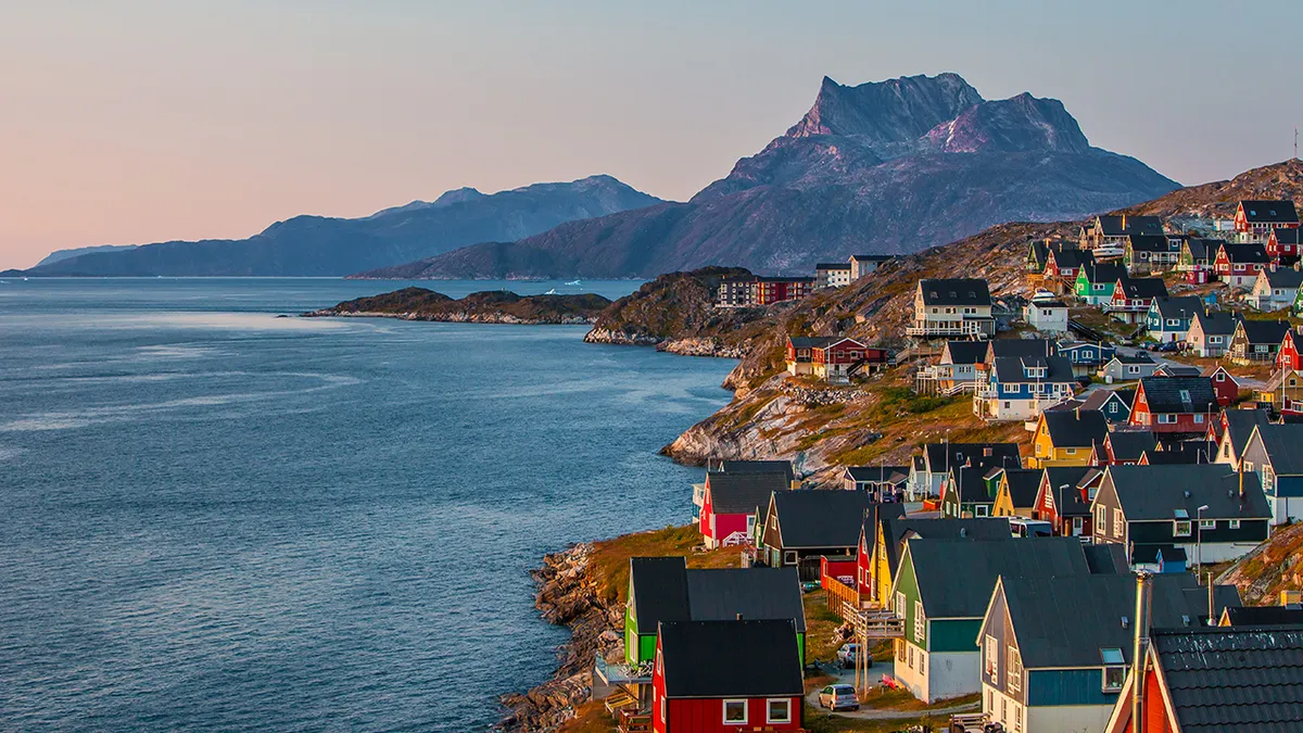 Šarene kuće duž stjenovite obale u Nuuk Grenlandu pri zalasku sunca
