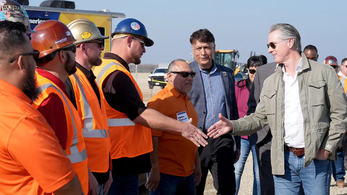 Guverner Kalifornije Gavin Newsom i glavni izvršni direktor Kalifornijske uprave za brze željeznice Ian Choudri rukuju se s članovima Iron Workers Local 155 na željezničkom mjestu