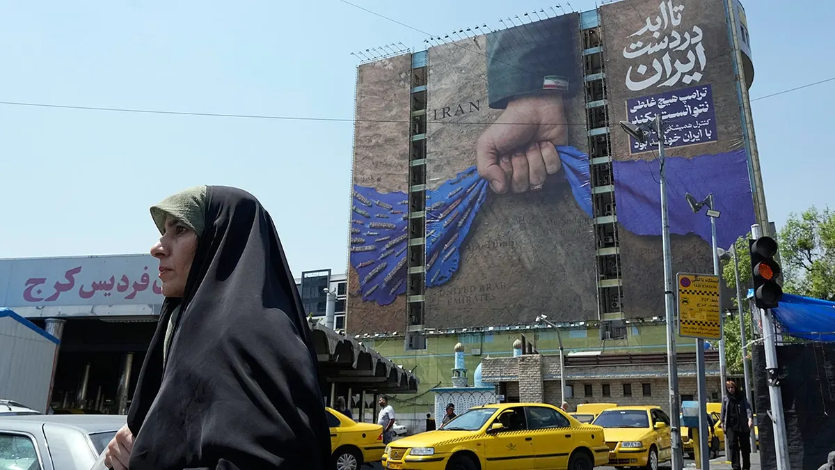 Žena prolazi pokraj reklamnog panoa koji prikazuje vojnu ruku koja drži Hormuški tjesnac u Teheranu