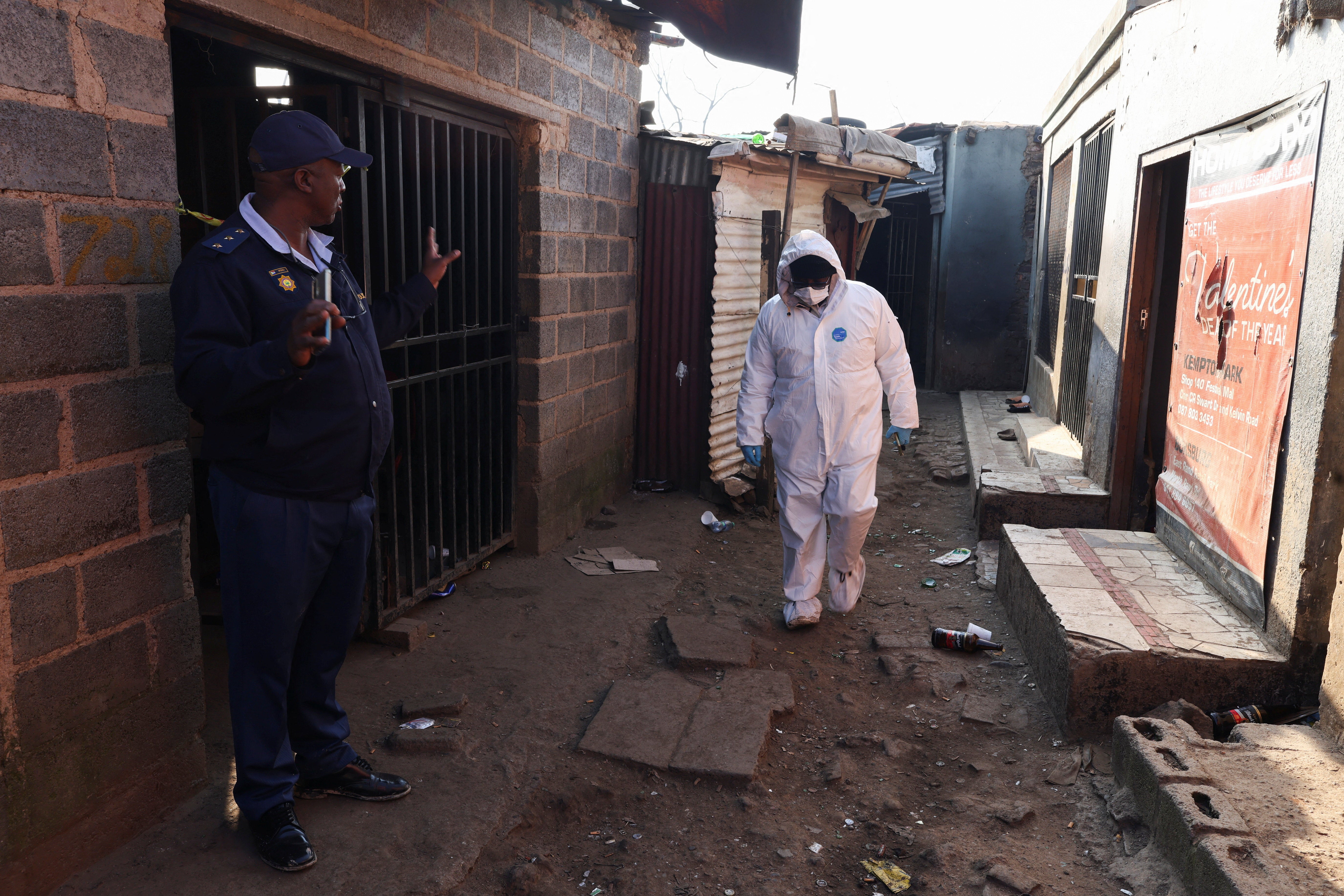 Policajac pokazuje pored člana forenzičkog tima nakon što su, prema policiji, naoružani napadači otvorili vatru u neformalnom naselju u Clevelandu, Johannesburg, Južnoafrička Republika, 10. lipnja 2026. REUTERS/Siphiwe Sibeko