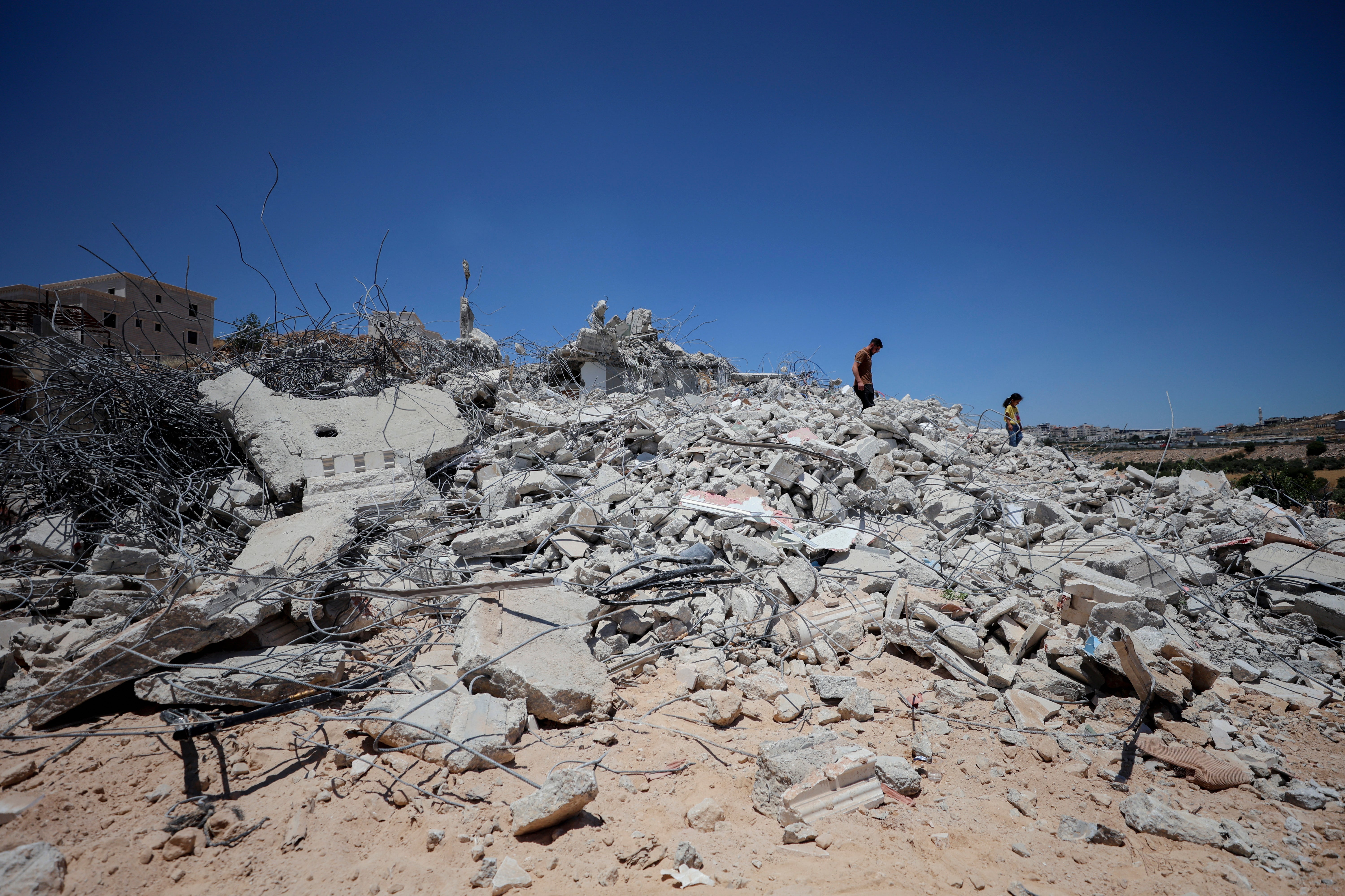 Palestinci hodaju među ruševinama srušene stambene zgrade u selu Khirbet Qalqas, južno od Hebrona, na okupiranoj Zapadnoj obali