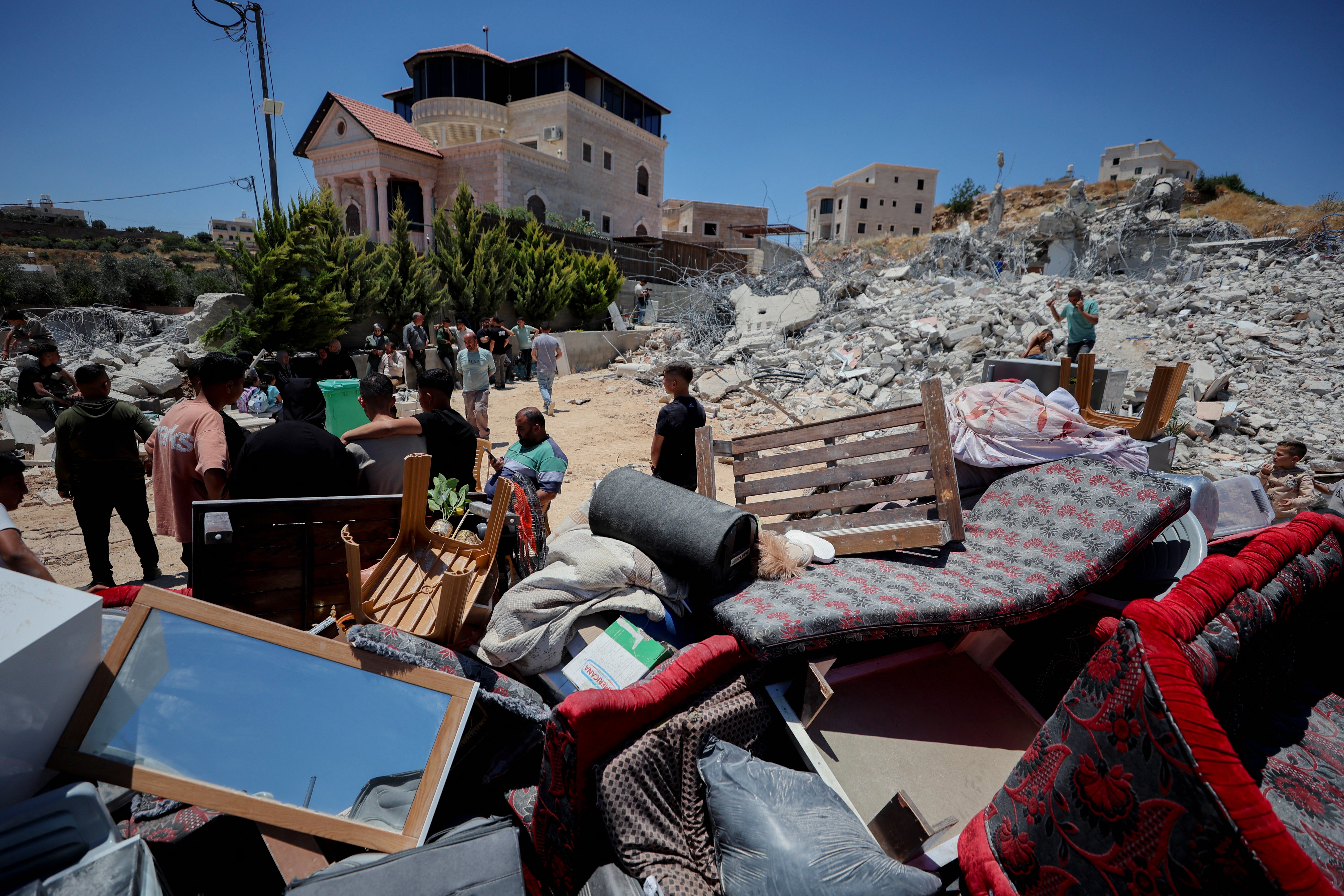 Palestinci se okupljaju kraj hrpe spašenog namještaja ispred ruševina srušene stambene zgrade u selu Khirbet Qalqas, južno od Hebrona, na okupiranoj Zapadnoj obali