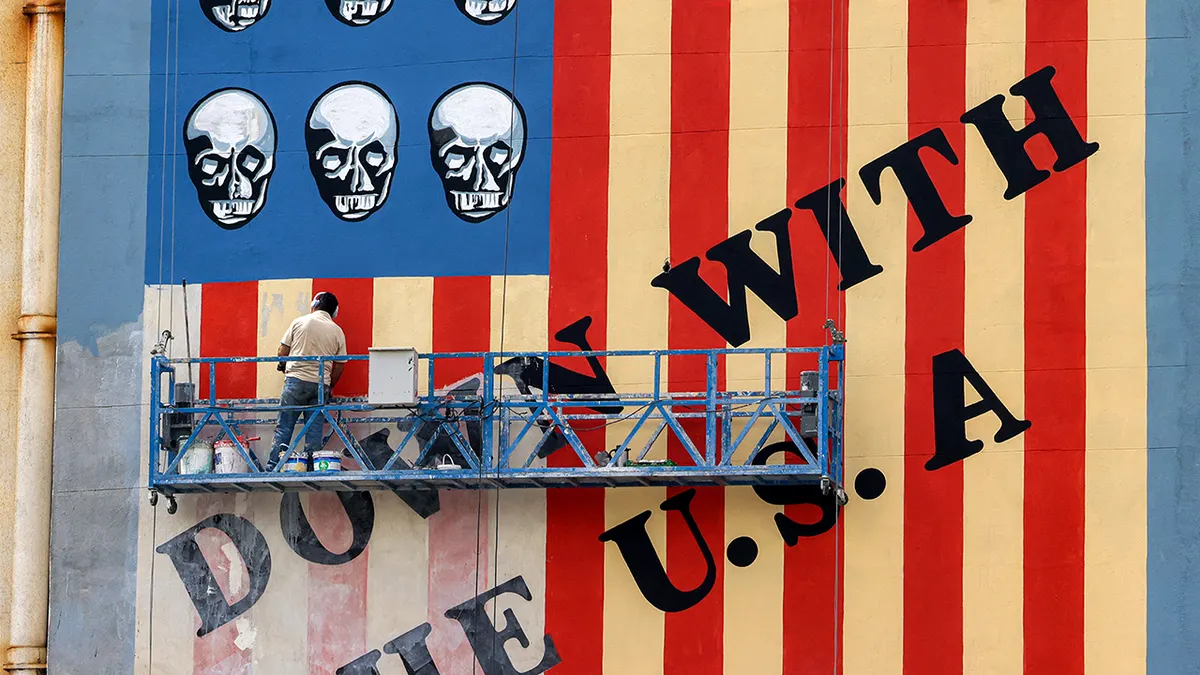 Čovjek slika mural protiv SAD-a na zidu zgrade na aveniji Karim Khan Zand u Teheranu