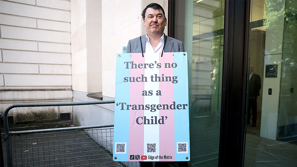 Graham Linehan drži plakat na kojem piše da transrodno dijete ne postoji ispred Prekršajnog suda u Londonu