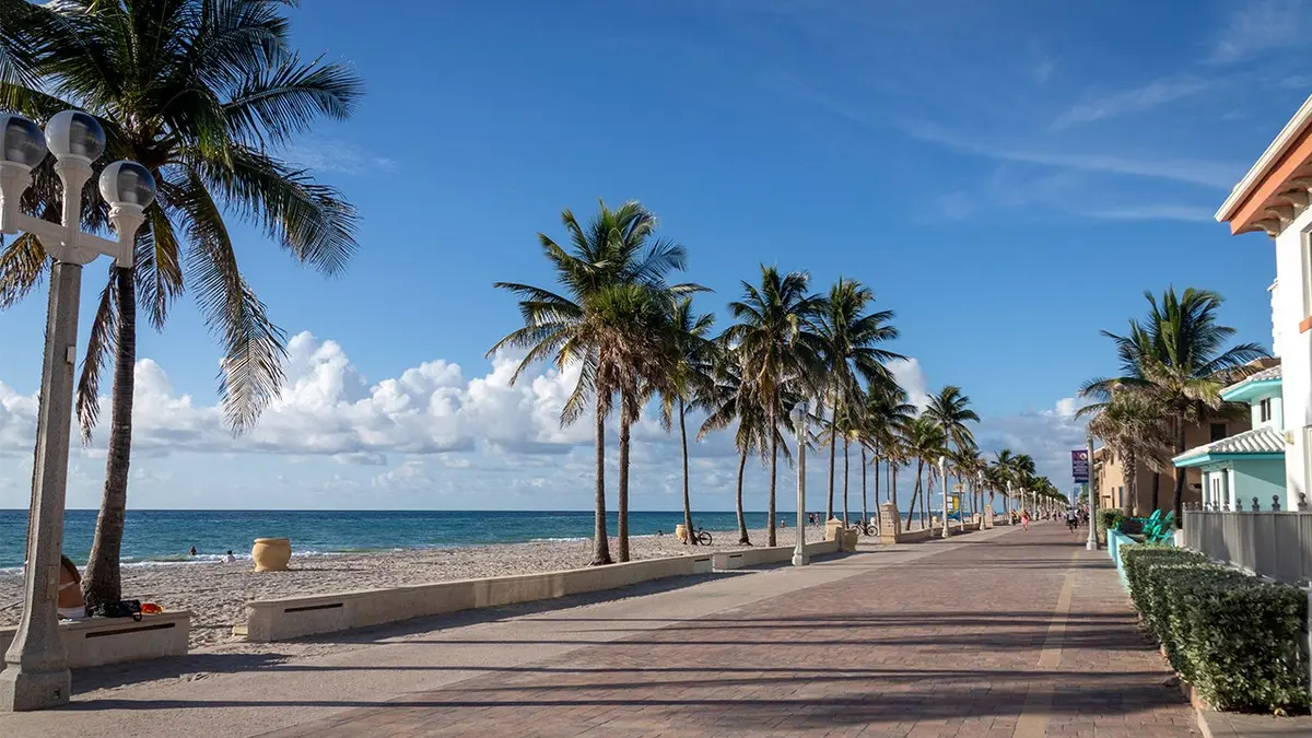 fotografija prikazuje plažu i šetnicu s palmama