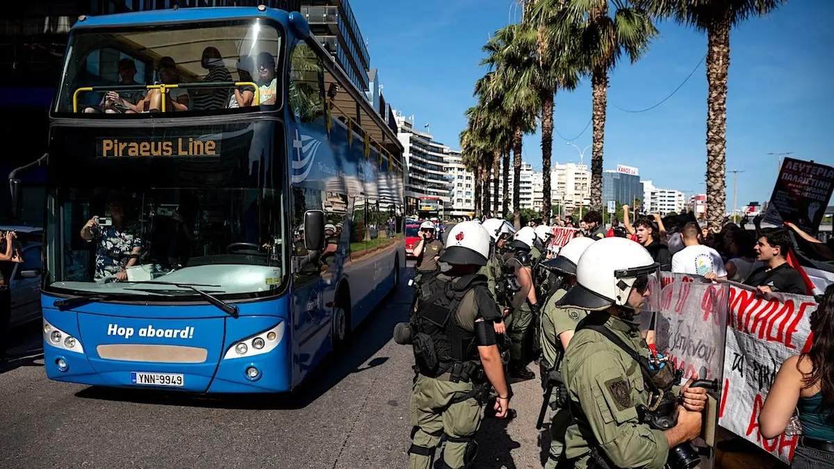 Izraelski turisti koji putuju autobusima pokraj propalestinskih prosvjednika i grčkih snaga sigurnosti u luci Pirej