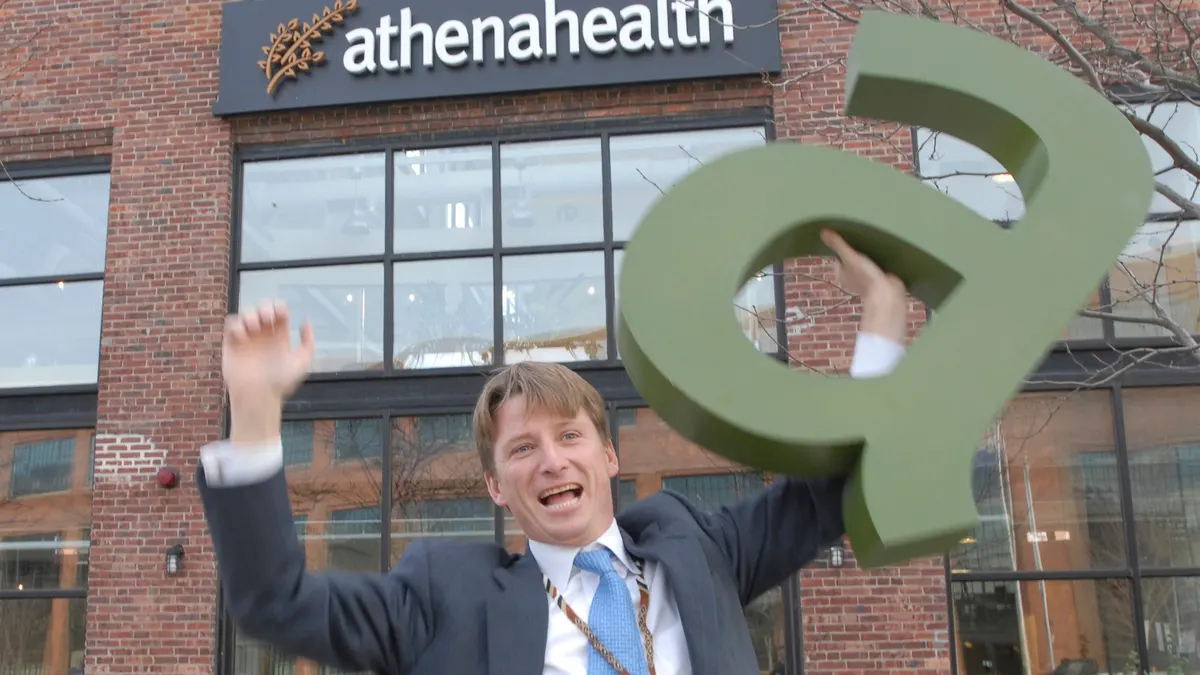 Jonathan J. Bush Jr. smiješi se i pokazuje unutar ureda athenahealtha u Watertownu u Massachusettsu