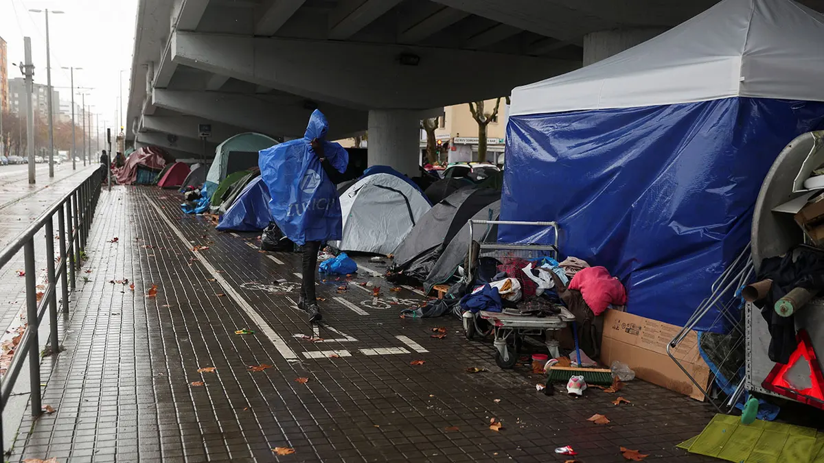Migrant prolazi pokraj improviziranog naselja u kojem migranti izbačeni iz bivše srednje škole prošli tjedan kampiraju na otvorenom usred zime u Badaloni, Španjolska