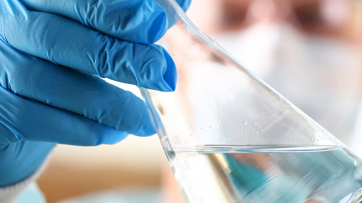 Muški znanstvenik drži prazne bočice pod rukom u laboratorijskom okruženju