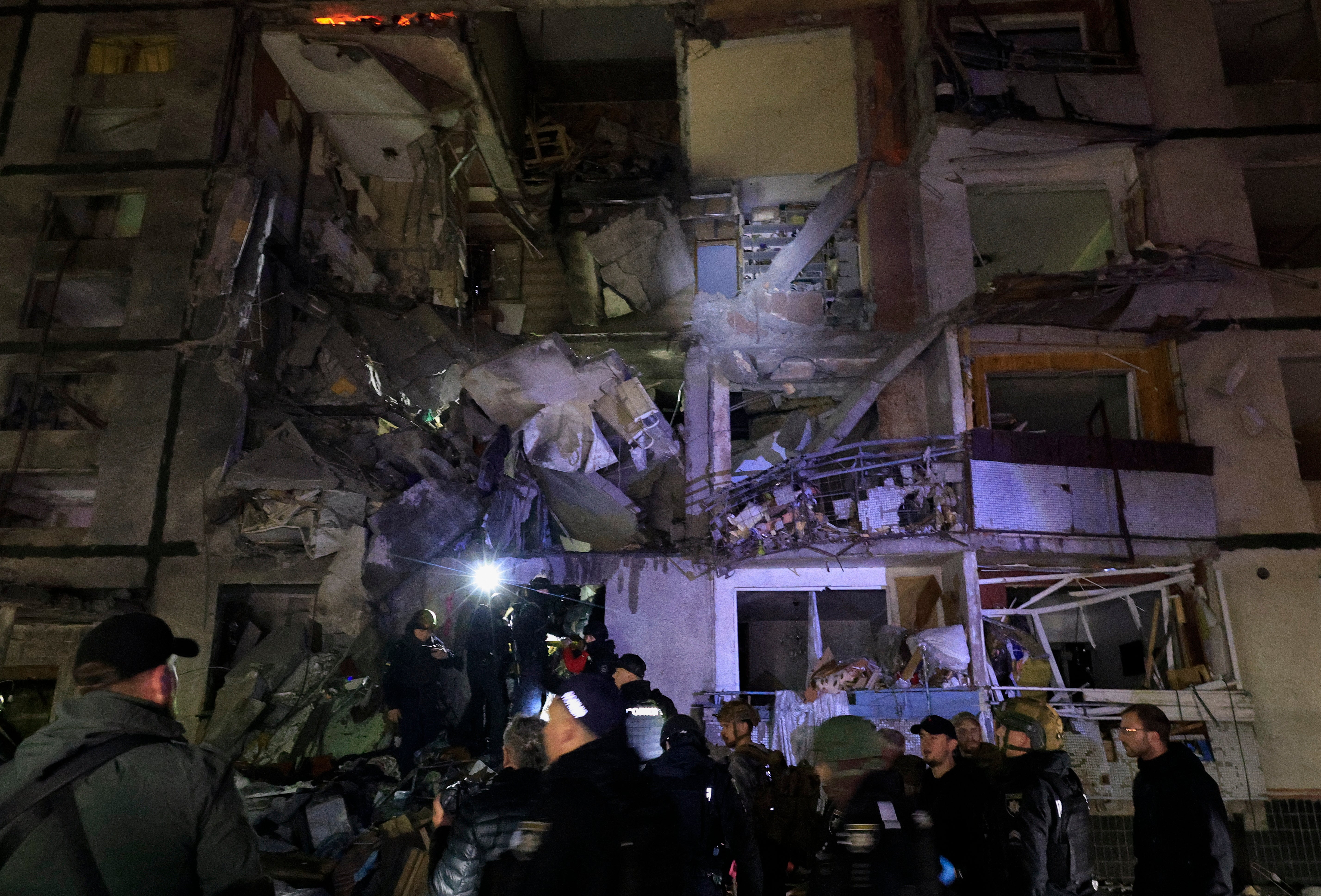 Ukrajinski spasioci rade na mjestu napada ruske jedriličarske bombe kasno noću na deveterokatnu stambenu zgradu u Harkovu