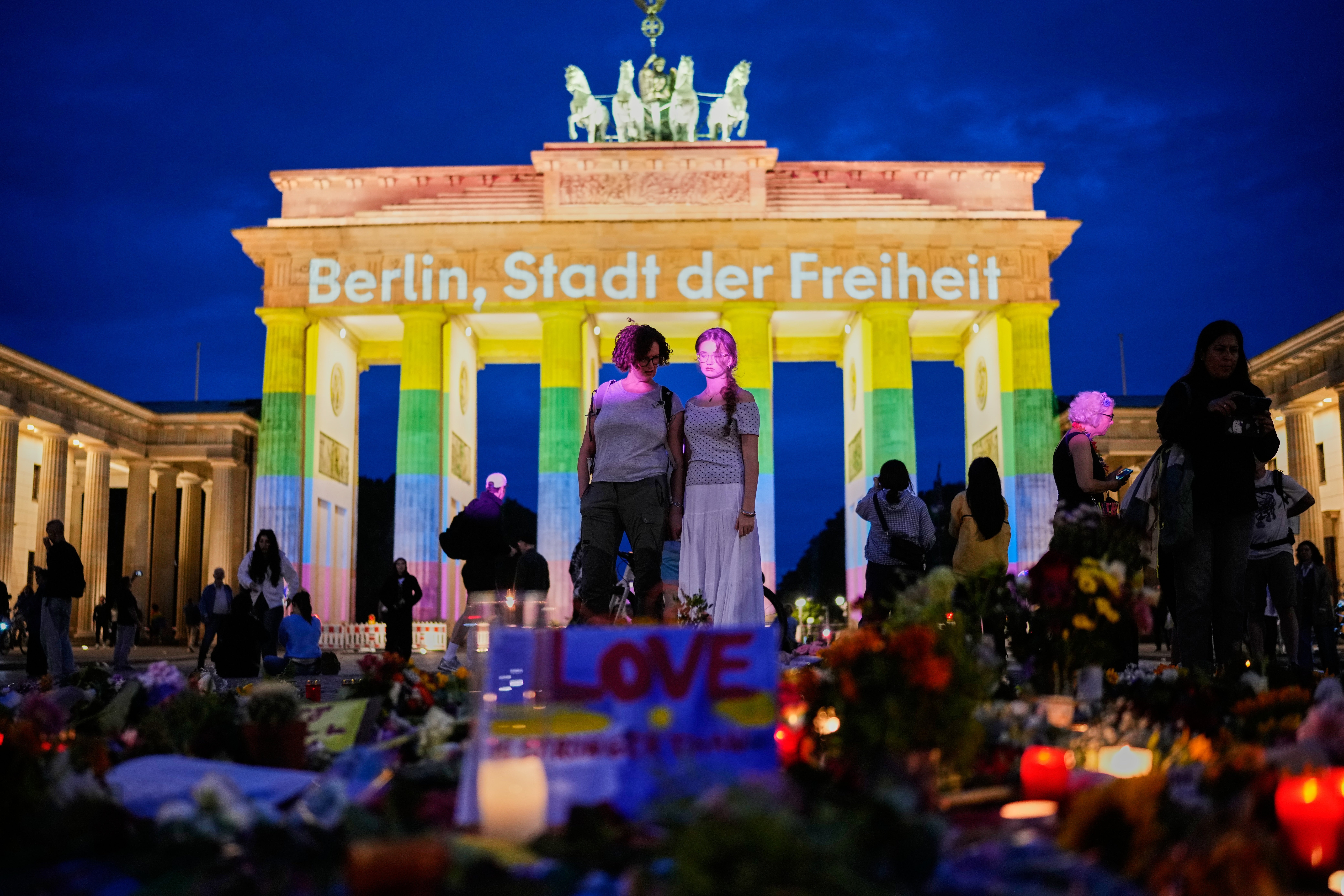 Ljudi se okupljaju ispred Brandenburških vrata osvijetljenih porukom 