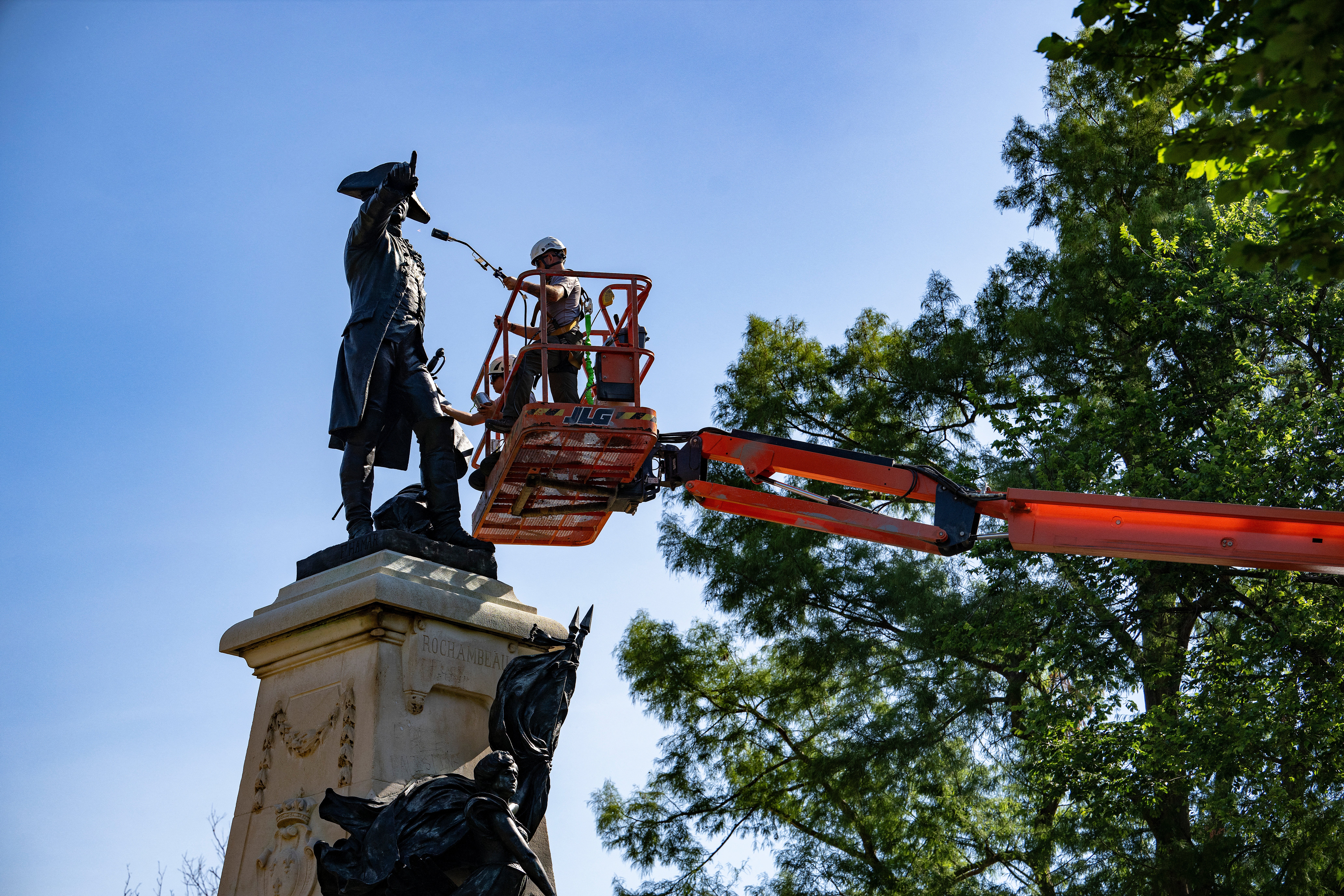 National Park Service employees paint and repair the Major General Comte Jean de Rochambeau bronze statue honoring a French nobleman and general who played a major role in helping the 13 Colonies win independence during the Revolutionary War, in Lafayette Park in Washington, DC, on July 2, 2024.