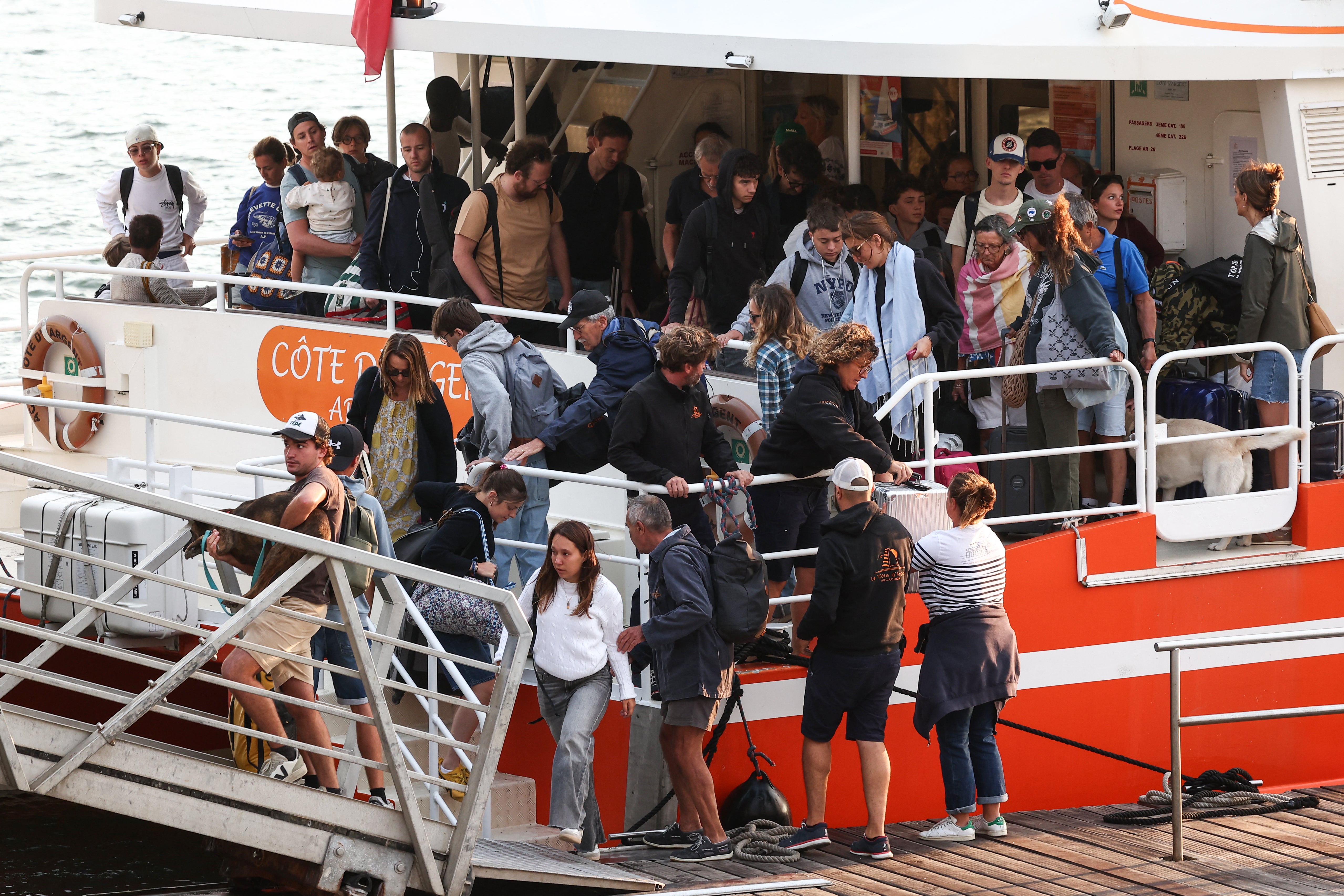 Turisti iz Lege-Cap-Ferret iskrcavaju se s broda po dolasku u Arcachon tijekom operacije evakuacije cijelog poluotoka Cap-Ferret