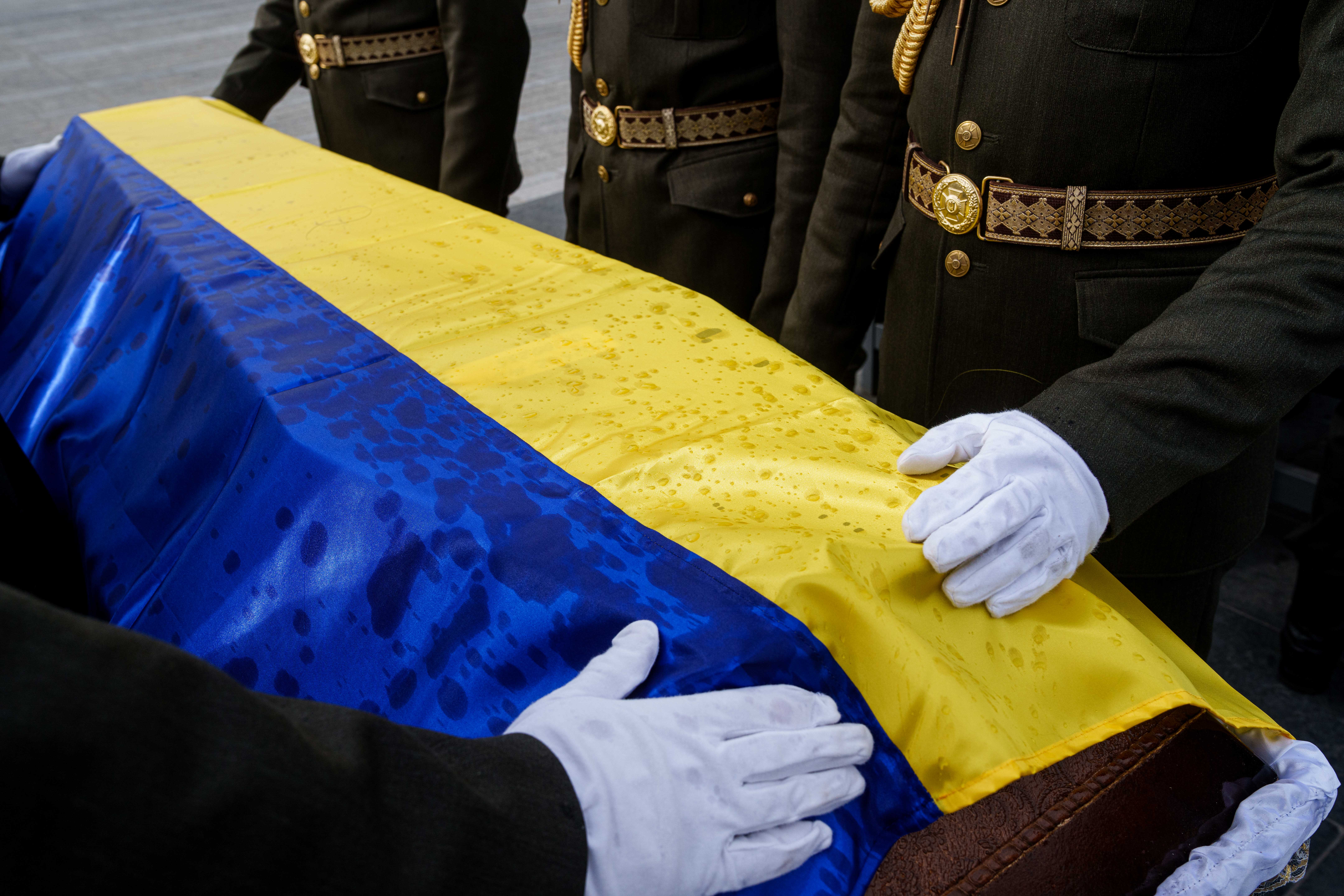 Počasna straža ispravlja zastavu okačenu na lijesu neidentificiranog ukrajinskog vojnika poginulog u bitci tijekom rusko-ukrajinskog rata (AP Photo/Evgeniy Maloletka)
