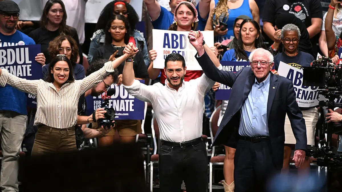 Alexandria Ocasio-Cortez, Abdul El-Sayed i Bernie Sanders drže se za ruke nakon predizbornog skupa.