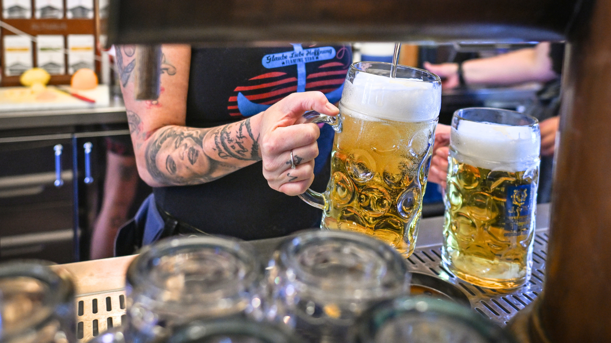 Žena se vidi kako toči pivo iz slavine u baru.