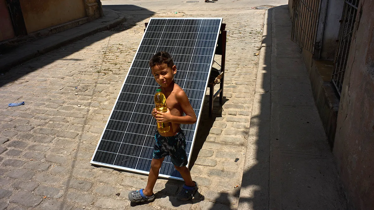 dječak drži bocu ulja u blizini solarne ploče