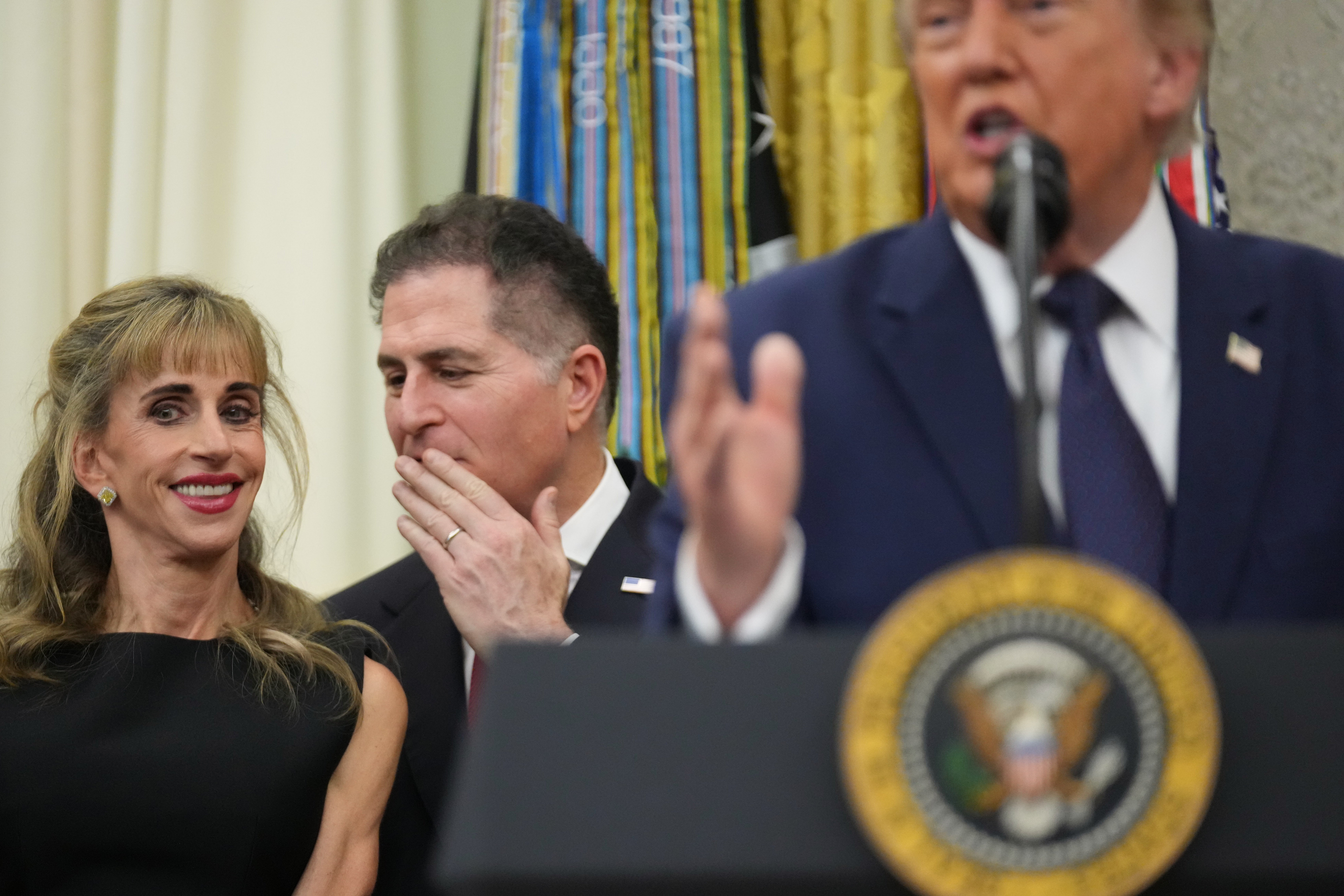 Michael Dell šapće svojoj supruzi Susan dok predsjednik Donald Trump govori nakon što je zazvonio otvaranje burze u New Yorku i Nasdaqa u Ovalnom uredu.
