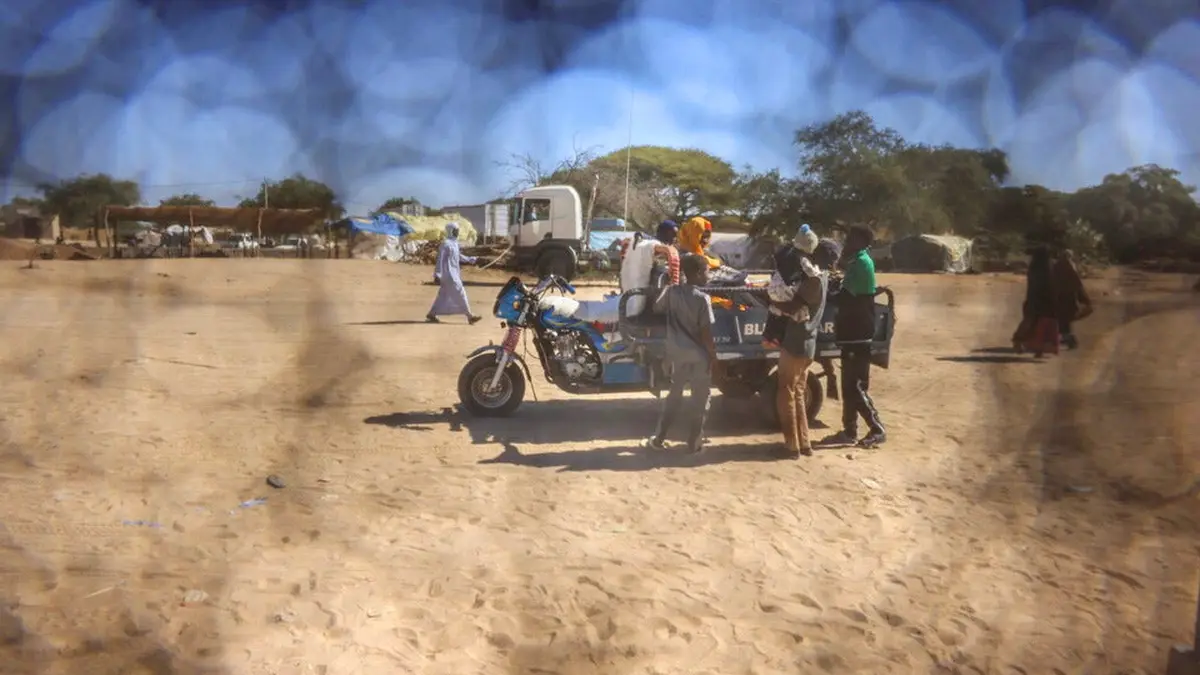 A Sudanese refugee father from Al-Fashir rides on a motorized cart with his family travelling between Chad and Sudan