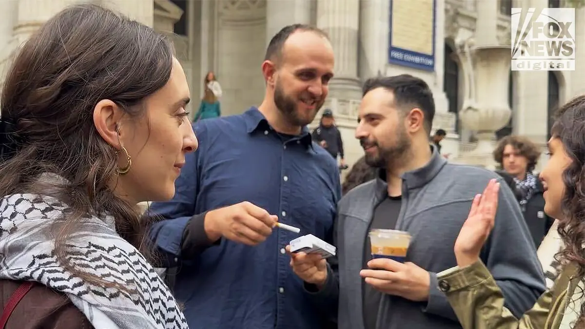 Palestinian Youth Movement organizer Taher Dahleh takes a cigarette while speaking with activists outside the New York Public Library as People’s Forum Education Director Layan Fuleihan stands at left.